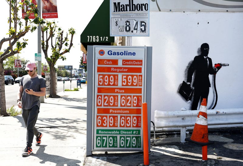 FILE - A person walks near street art (R) by artist Hijack on a wall next to gas prices being advertised on March 30, 2022 in Los Angeles.