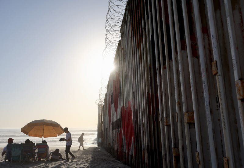TIJUANA, MEXICO - APRIL 07: Beachgoers gather near the U.S.-Mexico border barrier which extends into the Pacific Ocean