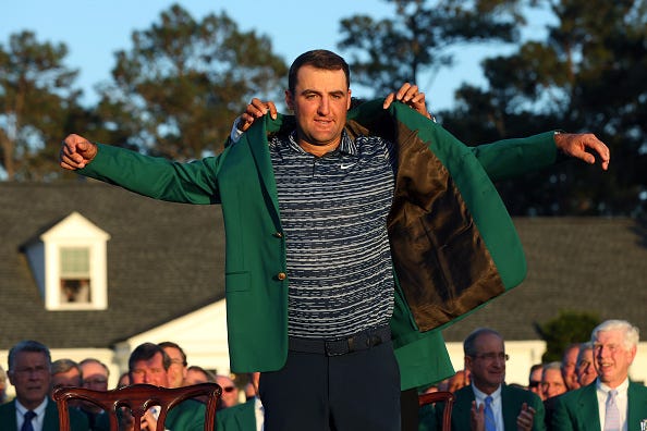  Scottie Scheffler is awarded the Green Jacket by 2021 Masters champion Hideki Matsuyama of Japan during the Green Jacket Ceremony after he won the Masters at Augusta National Golf Club on April 10, 2022 in Augusta, Georgia.