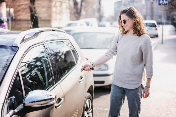 Woman pointing key fob at car