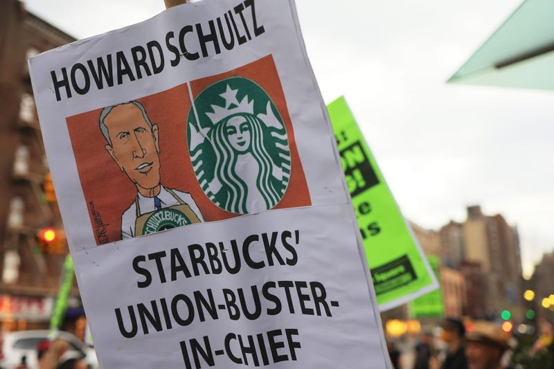 People hold signs while protesting in front of Starbucks on April 14, 2022 in New York City. Activists gathered to protest Starbucks' CEO Howard Schultz anti-unionization efforts and demand the reinstatement of workers fired for trying to unionize. 
