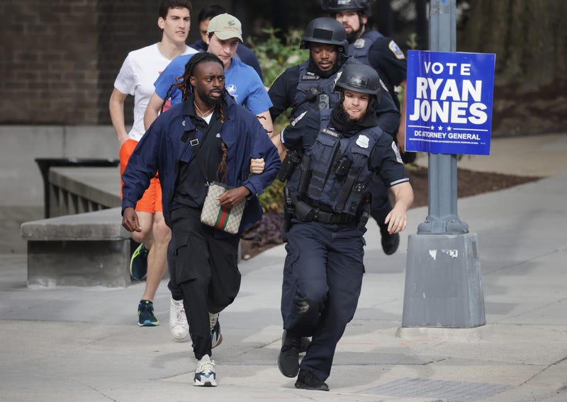 WASHINGTON, DC - APRIL 22: Metropolitan Police run as they escort people, some without shoes, away from a shooting scene in the northwest part of the city on April 22, 2022 in Washington, DC. Police evacuated residents from the shooting scene Friday afternoon and there were reports of several shooting victims.