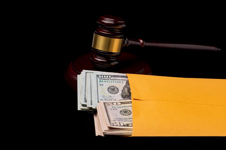 Courtroom gavel and cash money in envelope.