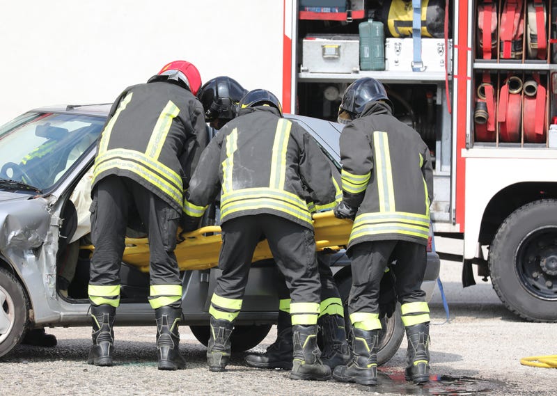 Firemen pull person from car crash scene.