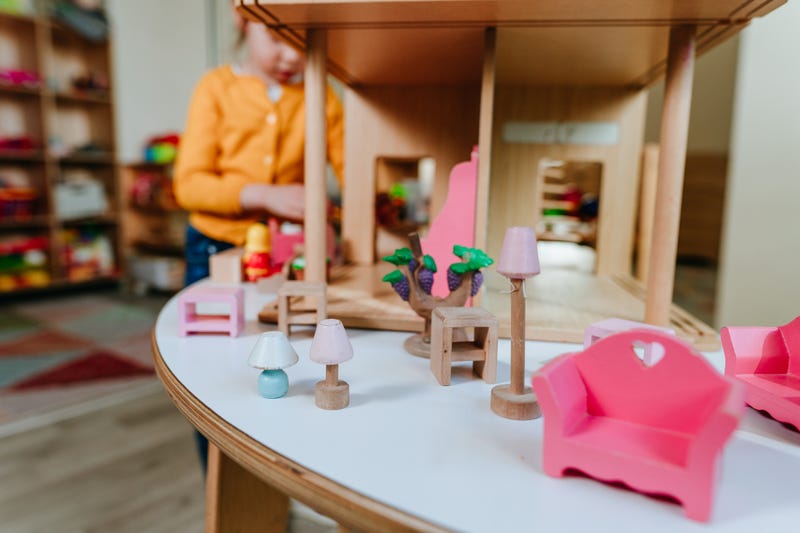 child plays with dollhouse toys in daycare center