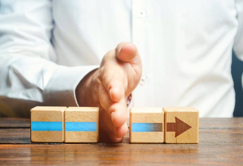 Man putting is hand in the middle of blocks with an arrow on them.