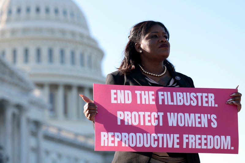 Cori Bush holding a sign that says "end the filibuster, protect women's reproductive freedom."
