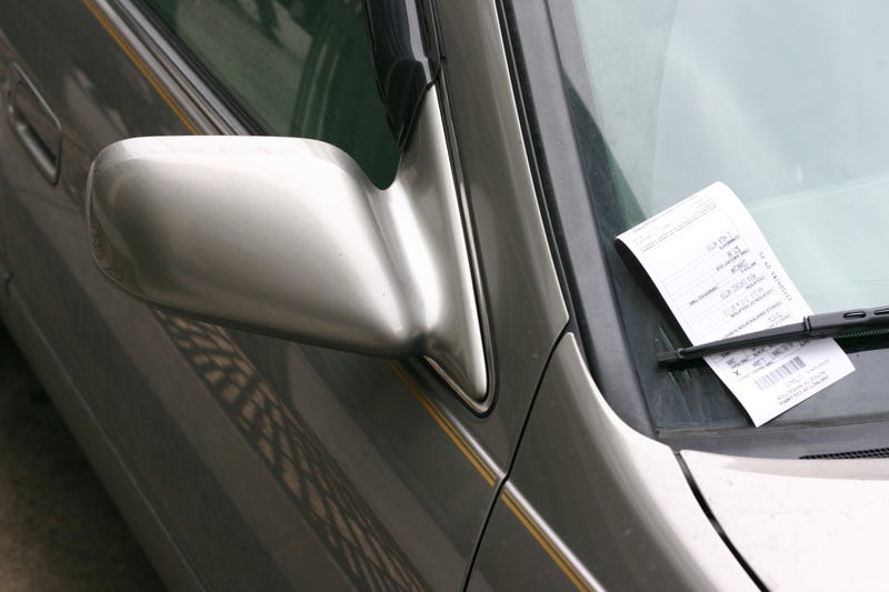 A parking ticket sits on a car's windshield.