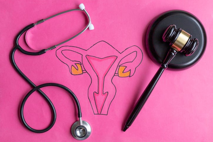 Female reproductive system next to a stethoscope and gavel depicting abortion and reproductive rights. 