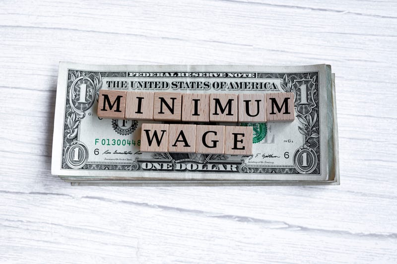 Minimum wage word written on wood block with American Dollar-bills