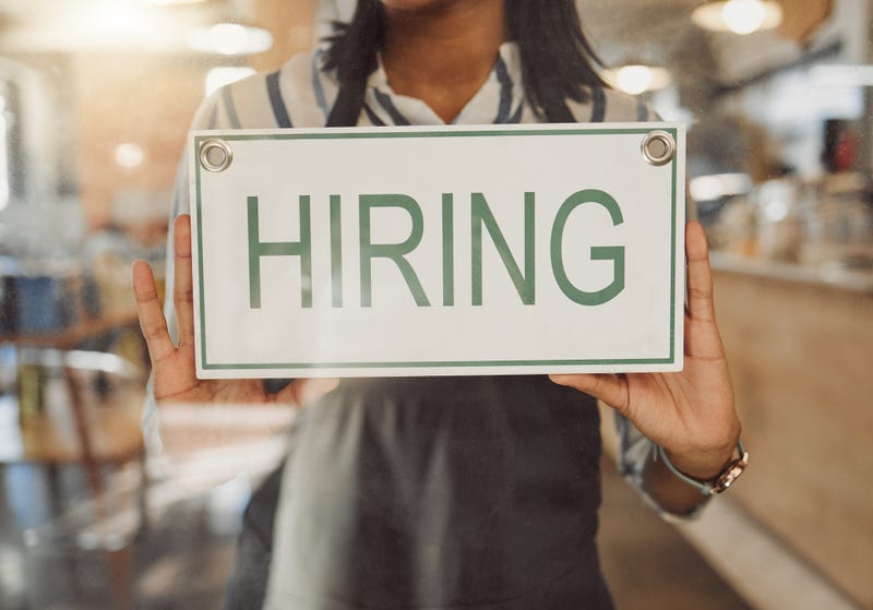 Worker hanging a hiring sign. 
