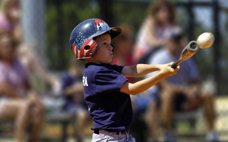 Young batter hitting baseball