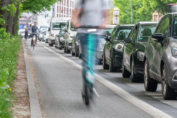 Riding electric scooters in bike lane past traffic jam