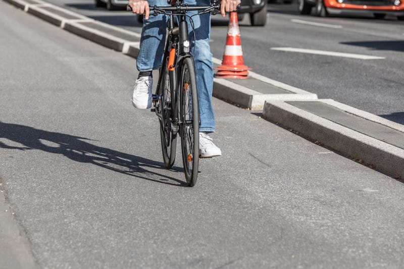 person riding a bike in a bike lane that has a short concrete barrier between bike and car lanes