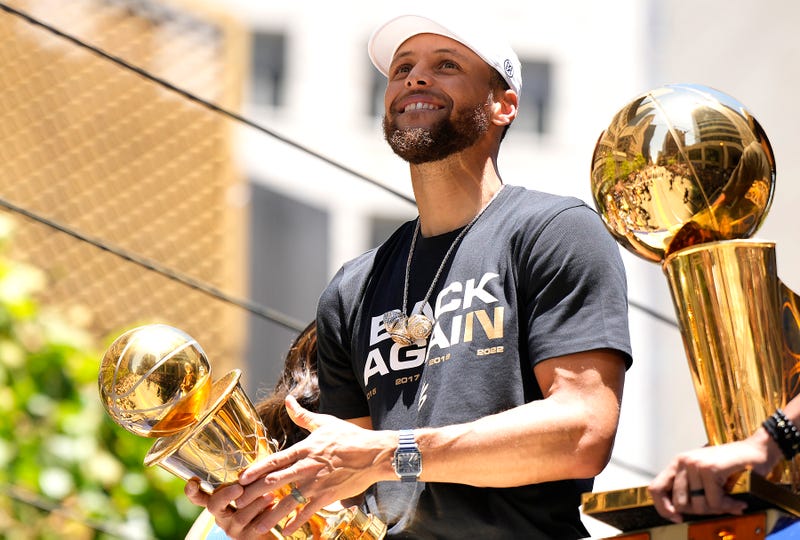 Stephen Curry #30 of the Golden State Warriors celebrates with the NBA Championship Trophy and his NBA Finals Most Valuable Player Award during the Golden State Warriors Victory Parade on June 20, 2022 in San Francisco, California.