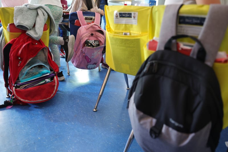 Student backpacks hang on the backs of classroom chairs at a New York City public school