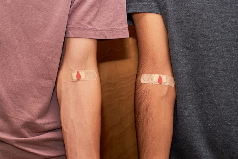 two men with bandaids on their arms after blood donation