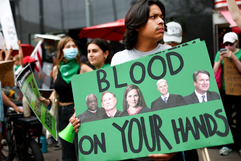 An abortion-rights activist holds a sign depicting Supreme Court Justices Clarence Thomas, Samuel A. Alito, Jr., Amy Coney Barrett, Neil M. Gorsuch, and Brett M. Kavanaugh during a demonstration outside a Planned Parenthood clinic as they safeguard the clinic from a possible protest by a far-right group on July 16, 2022 in Santa Monica, California