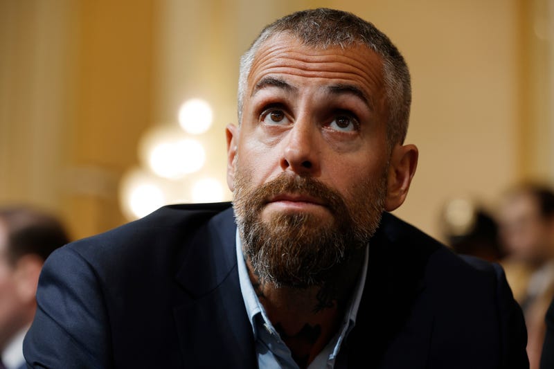 close up of michael fanone. he has short gray hair and a gray and brown goatee and wears a black suit