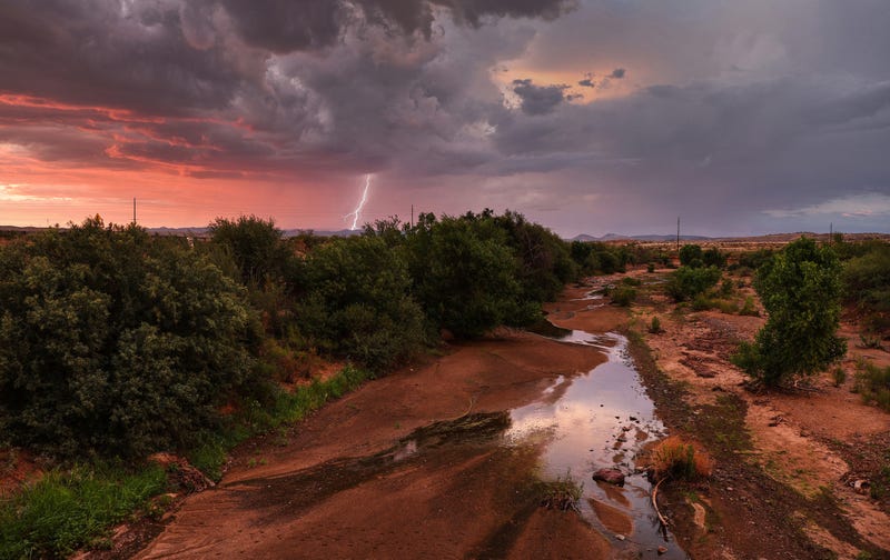 MAYER, ARIZONA - JULY 21: Lightning strikes during a monsoon storm with a nearly dry creek bed in the foreground on July 21, 2022 near Mayer, Arizona. The National Weather Service issued an excessive heat warning for eight counties in Arizona today including Yavapai county. Climate change is making heat waves more frequent and hotter with large swathes of the U.S. currently under excessive heat warnings. Six cities in Arizona, including Phoenix, have declared water shortages amid a climate change-fueled megadrought in the Southwestern United States.