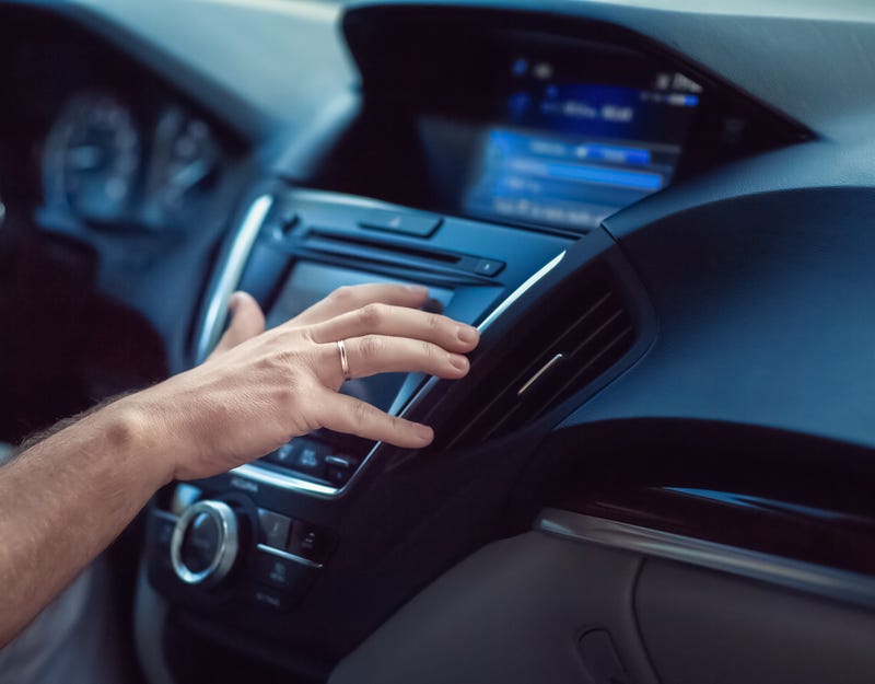 Person changing radio dial in car