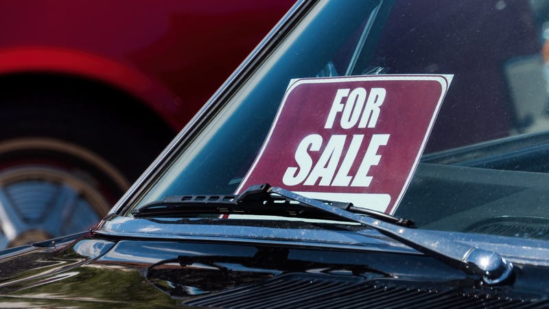 A FOR SALE sign behind the windshield on an old car