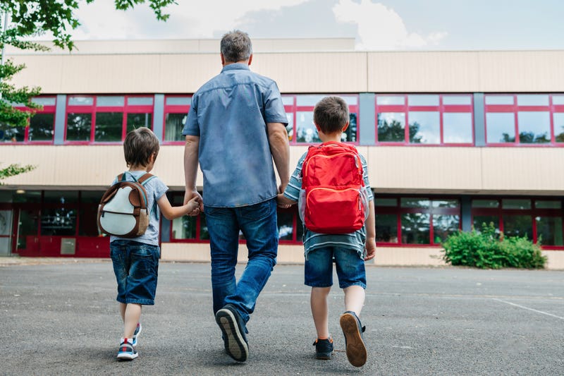 Parent walking his kids back to school. 
