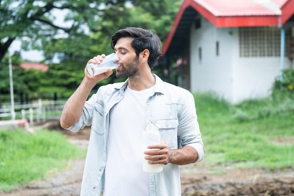 Man drinking milk while standing outside