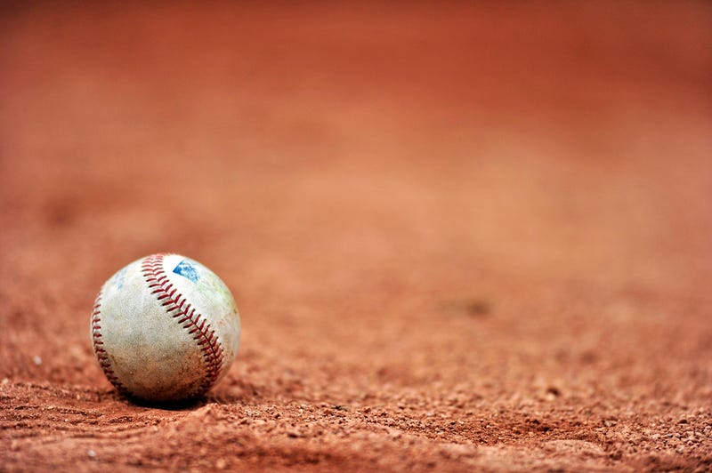 Baseball lying on a dirt field. 