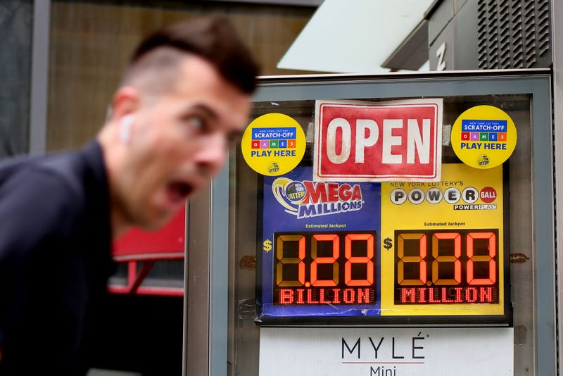 A man rides a bike past advertisements for the Mega Millions and Powerball lottery on July 29, 2022, in New York City.