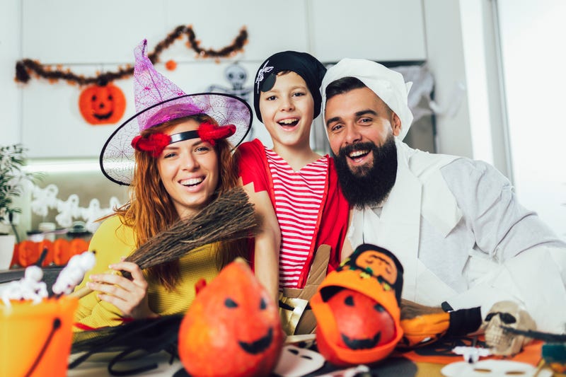 A mother, father, and son smiling in their Halloween costumes. 