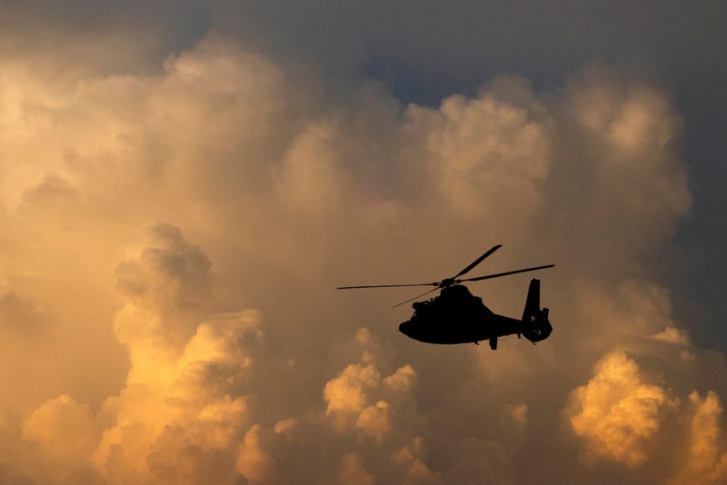 A U.S. Coast Guard helicopter in silhouette against a cloudy sky in a composite image.