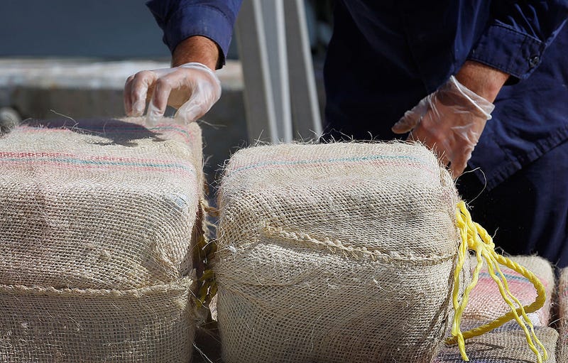 A crewmember from the Coast Guard Cutter Northland stands helps unload approximately 3,500 pounds of cocaine confiscated from a 35-foot go-fast vessel in the Caribbean Sea at Base Miami Beach on March 16, 2012 in Miami Beach, Florida. The 54 bales of cocaine were intercepted on March 3rd during a patrol and have a street value of $43,254,000. (Photo by Joe Raedle/Getty Images)