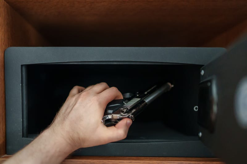 someone places a gun into a gun safe
