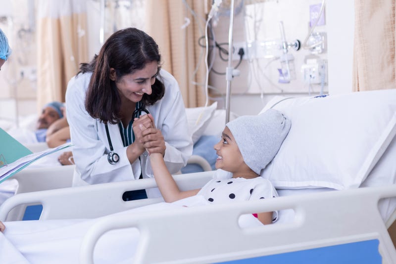 Female doctor giving high five to little girl patient at hospital.