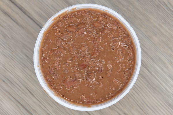 Plastic container of refried beans on wooden table