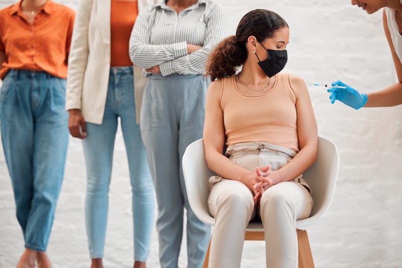 Woman getting a COVID-19 booster, with a line behind her. 
