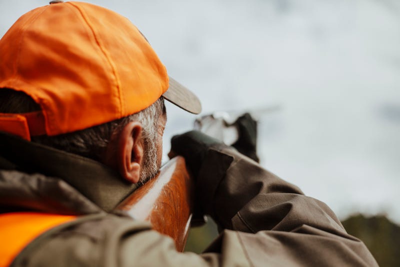 Hunter raising his firearm. 