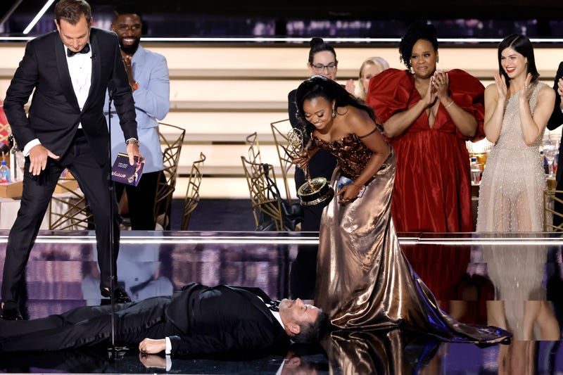 Quinta Brunson (R) accepts Outstanding Writing for a Comedy Series for "Abbott Elementary" from Will Arnett (L) while Jimmy Kimmel lies onstage during the 74th Primetime Emmys at Microsoft Theater on September 12, 2022 in Los Angeles, California.