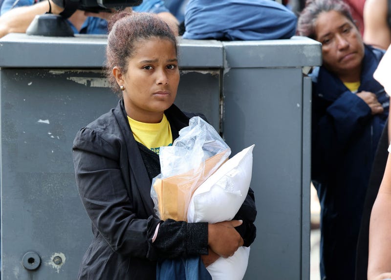 Migrants from Central and South America wait near the residence of US Vice President Kamala Harris after being dropped off on September 15, 2022 in Washington, DC. Texas Governor Greg Abbott dispatched buses carrying migrants from the southern border to Harris' home early Thursday morning. (Photo by Kevin Dietsch/Getty Images)