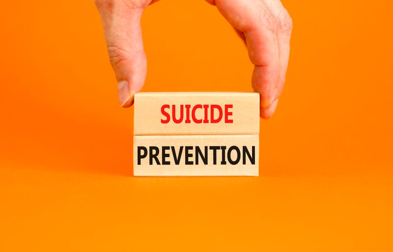 Suicide prevention written on blocks in front of an orange background. Stock photo.