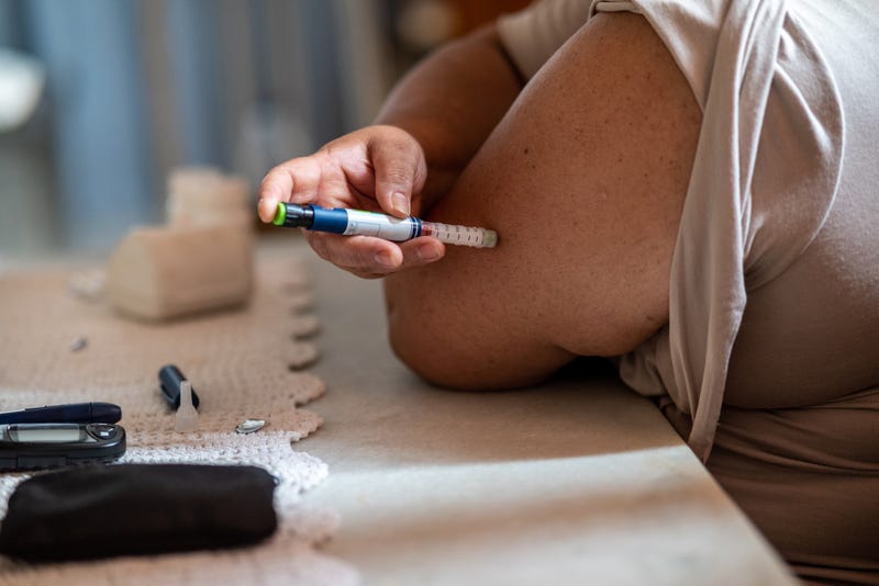 woman injects insulin in upper arm