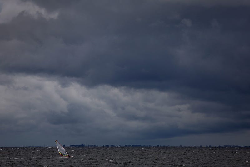 A windsurfer cruises through the water as clouds from the approaching Hurricane Ian darken the sky on Sept. 27, 2022, in St Petersburg, Florida. Hurricane Ian is expected to make landfall in the Tampa Bay area Wednesday night into early Thursday morning.