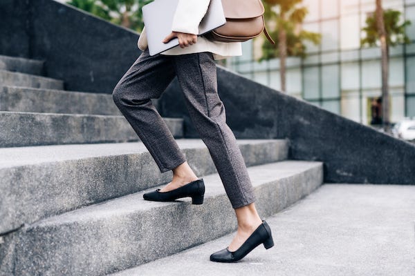Businesswomen carrying laptop walking up steps