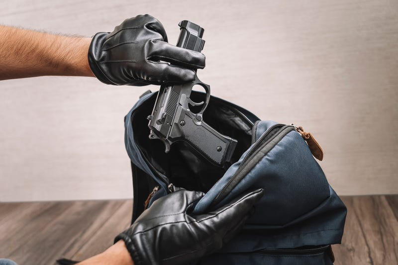 Gloved hands pulling gun out of luggage