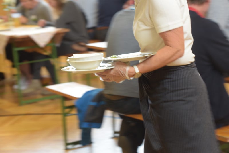 A waitress in a restaurant is serving food to the costumers