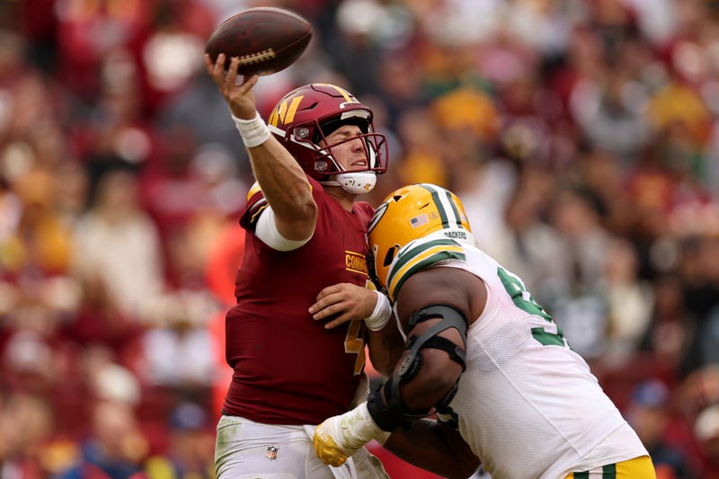 Washington Commanders quarterback Taylor Heinicke throws a pass while being hit during the team's Week 7 victory over the Green Bay Packers on October 23, 2022.