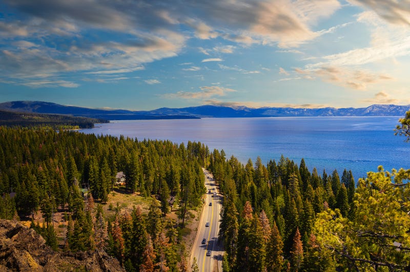 unset view from the Eagle Rock at Lake Tahoe and nearby road, California, with Sierra Nevada Mountains in the background.