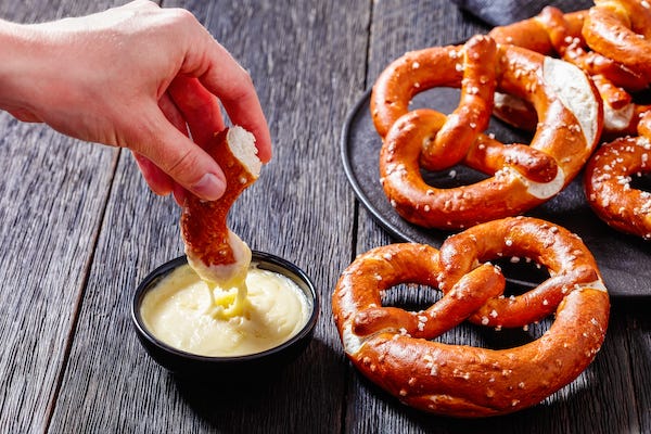 Pretzels in the form of knot with cheese sauce