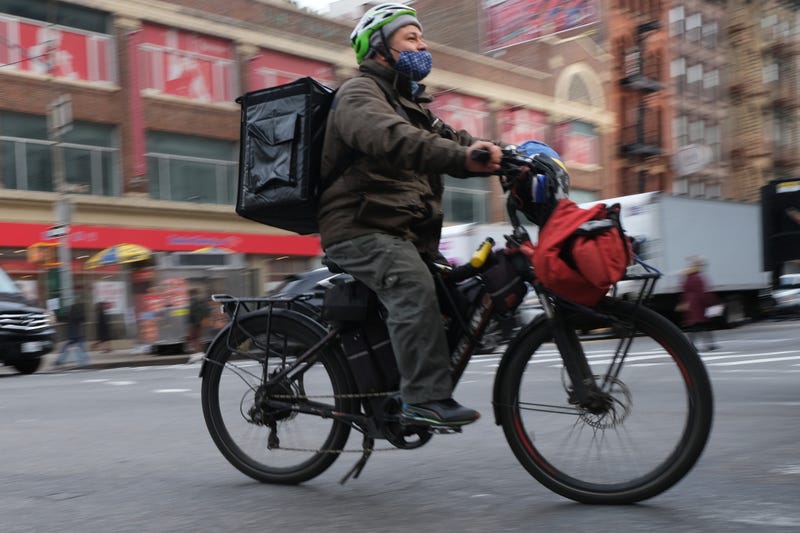 A delivery person rides an electric bicycle through the streets of Manhattan